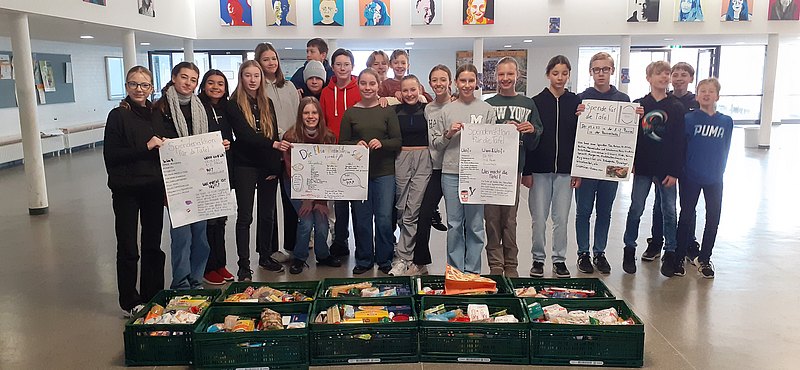 Eine Gruppe von Schüler:innen zeigt selbstgemachte Plakate einer Spendenaktion an die Hannöversche Tafel